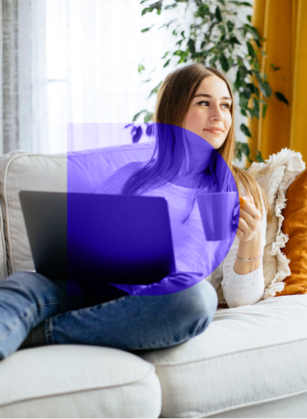 Woman sitting on the couch holding coffee and a laptop