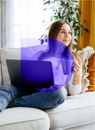 Woman sitting on the couch holding coffee and a laptop