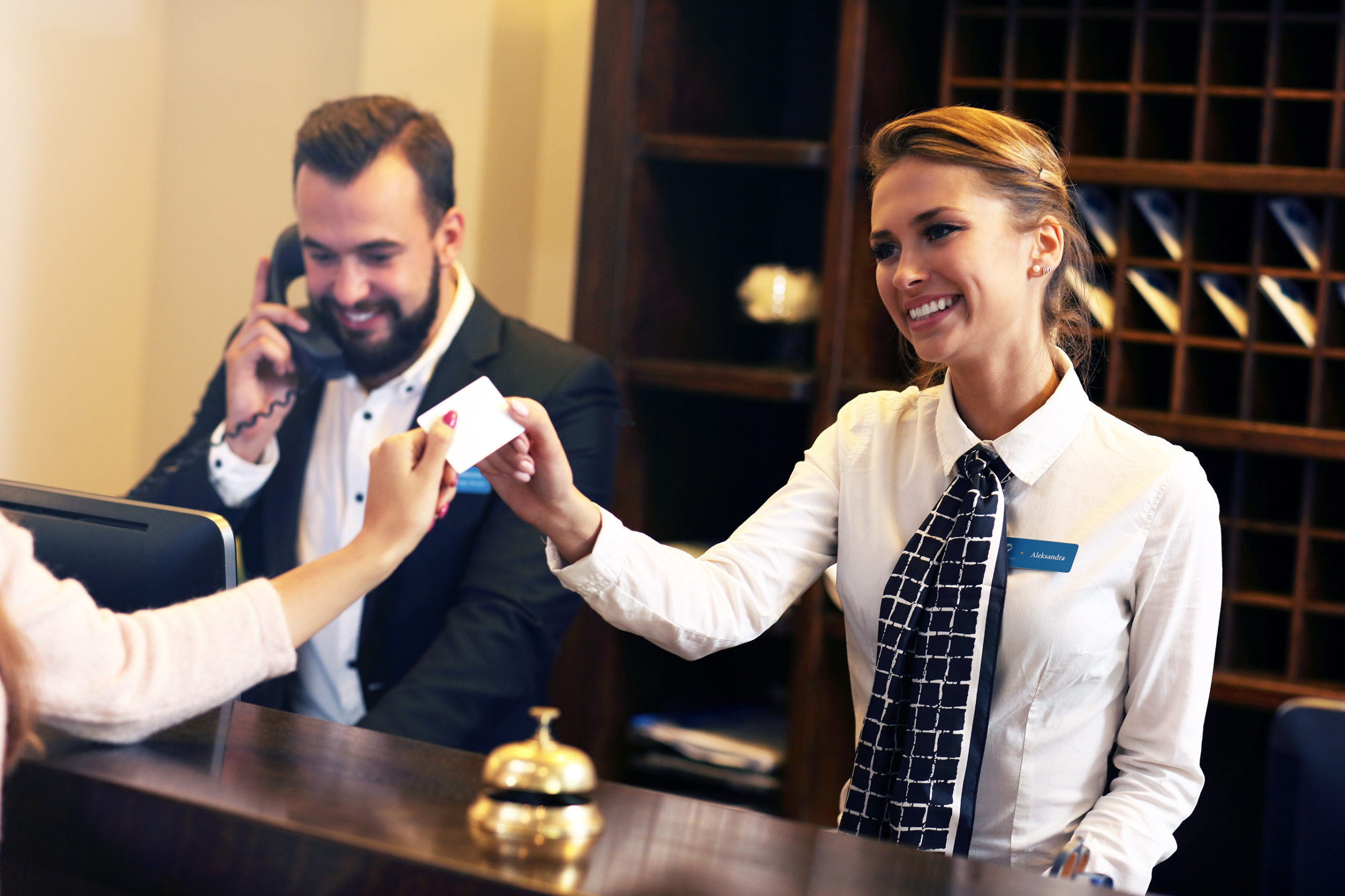 smiling hotel receptionist receiving a credit card from a guest
