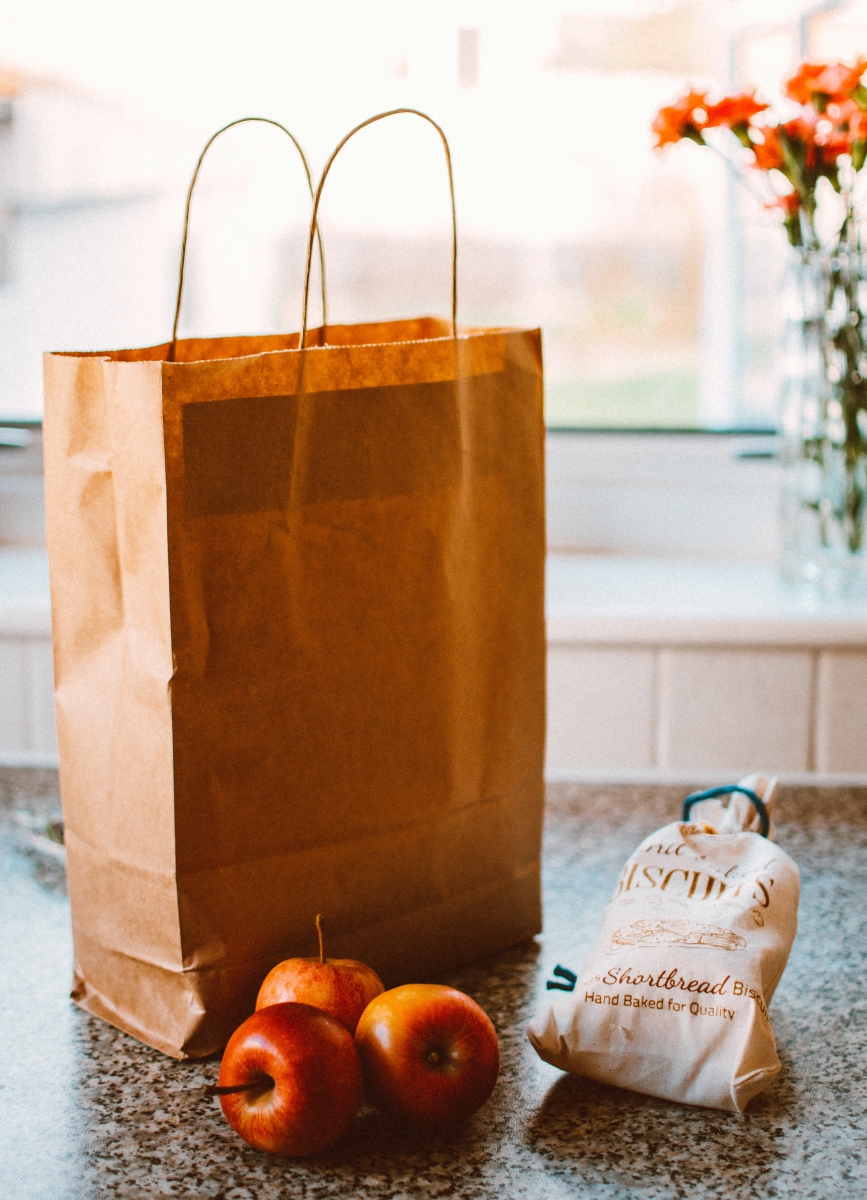 few apples beside a grocery bag