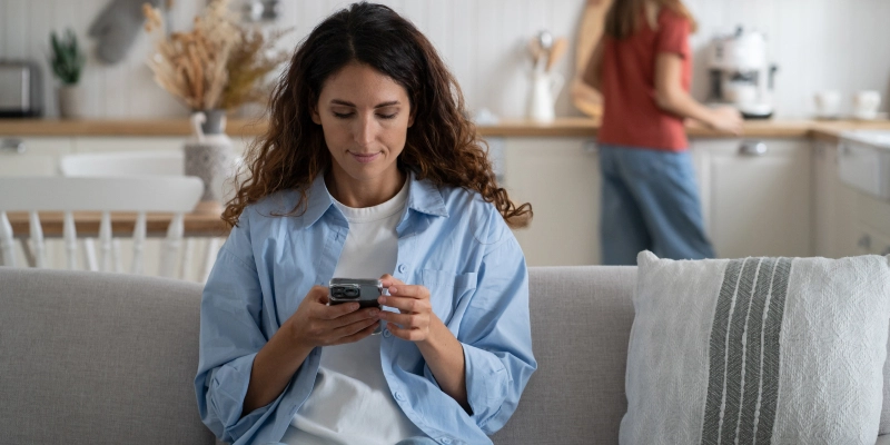 woman sitting on a sofa looking at her phone