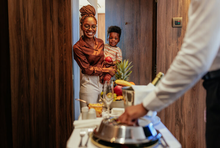 mom holding her child while opening the door for hotel room service
