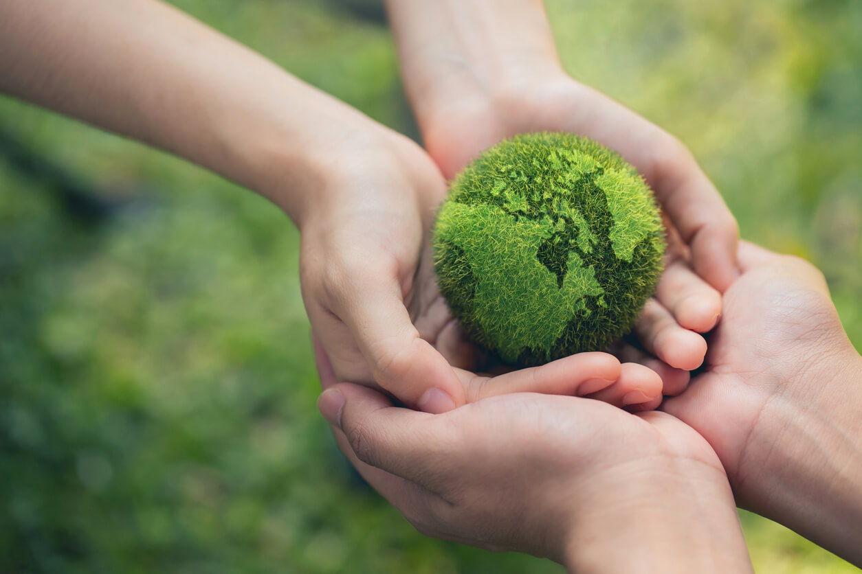 hands holding a green replica of earth